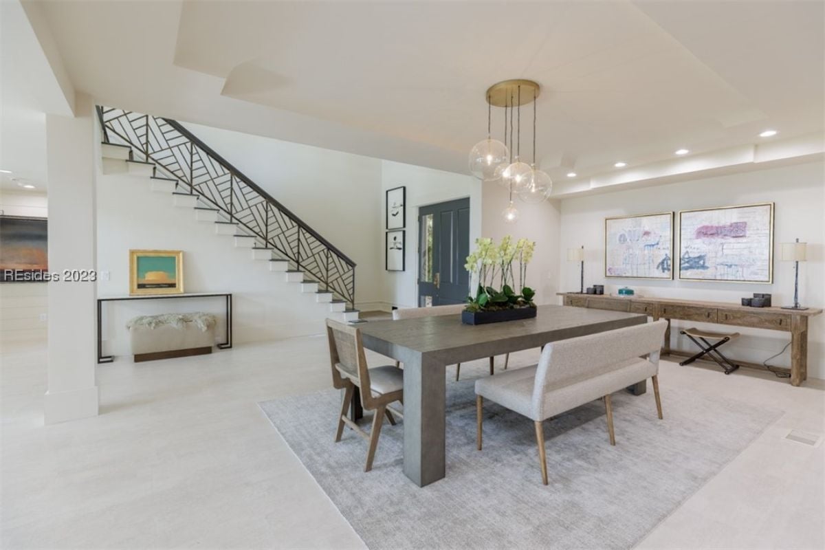 Dining room with custom lighting, tile flooring and a large table.