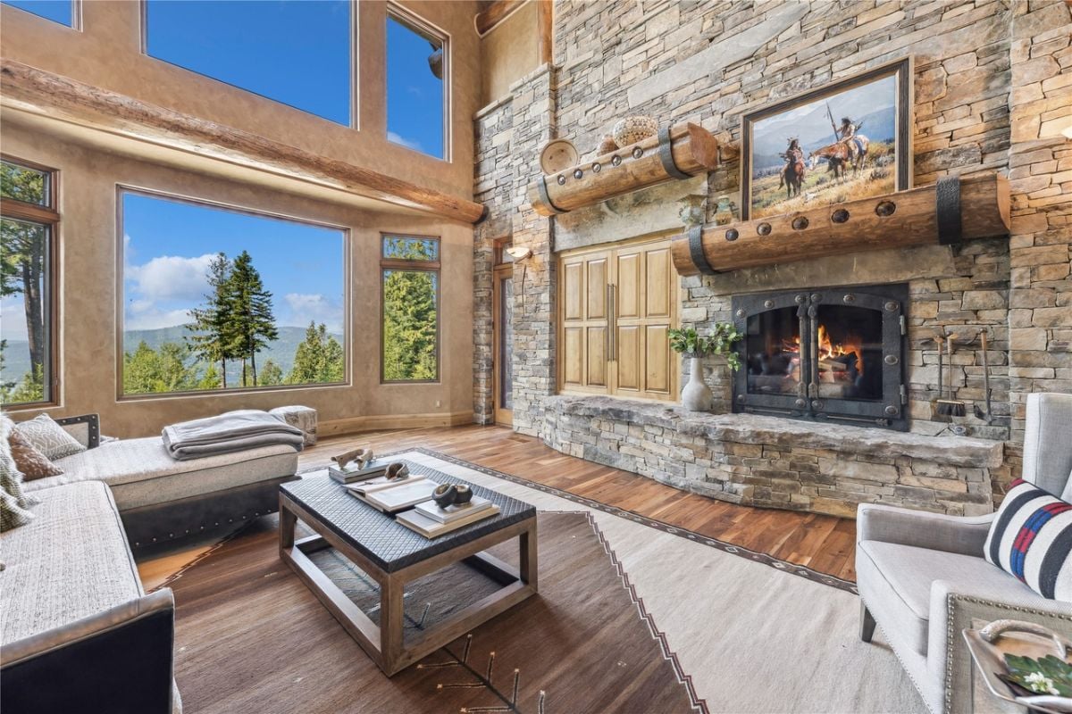 Living room with couches. huge glass windows, fireplace, and wood flooring.