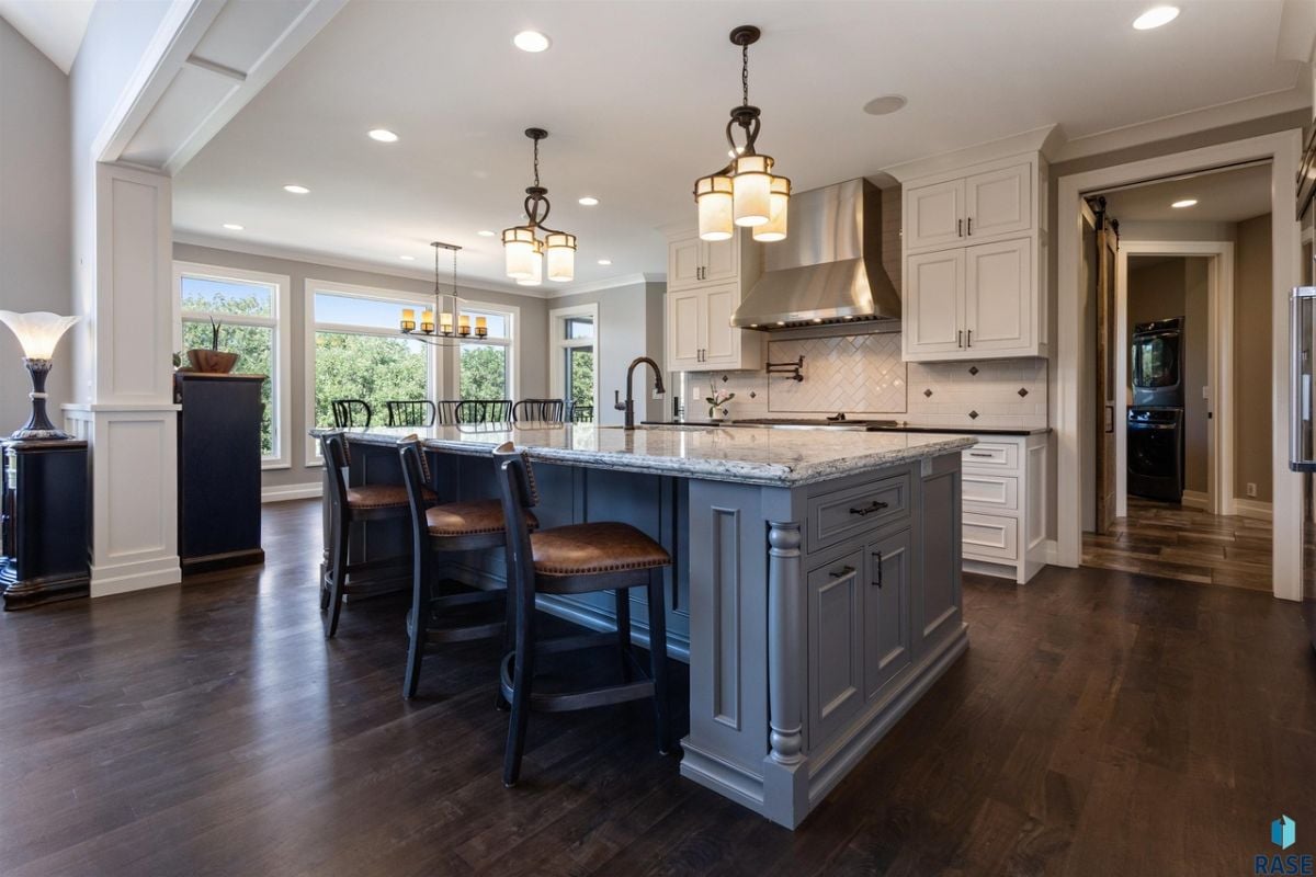 Kitchen with center island, custom lighting and wood flooring.