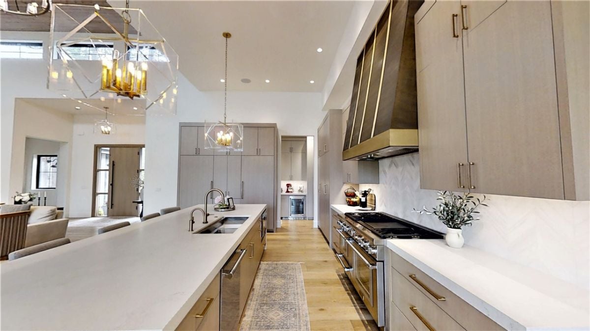 Kitchen with a large island, custom cabinetry, and custom lighting.