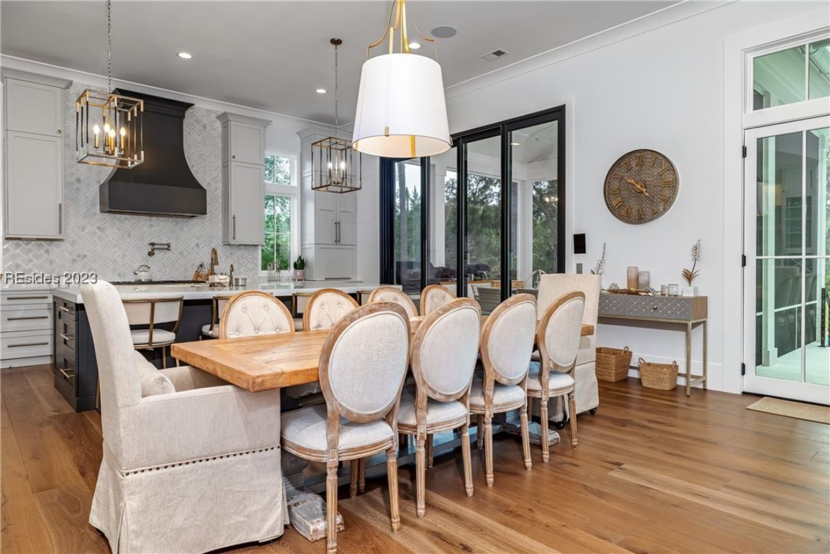 Dining room with wood flooring, custom lighting, and a large wooden table.