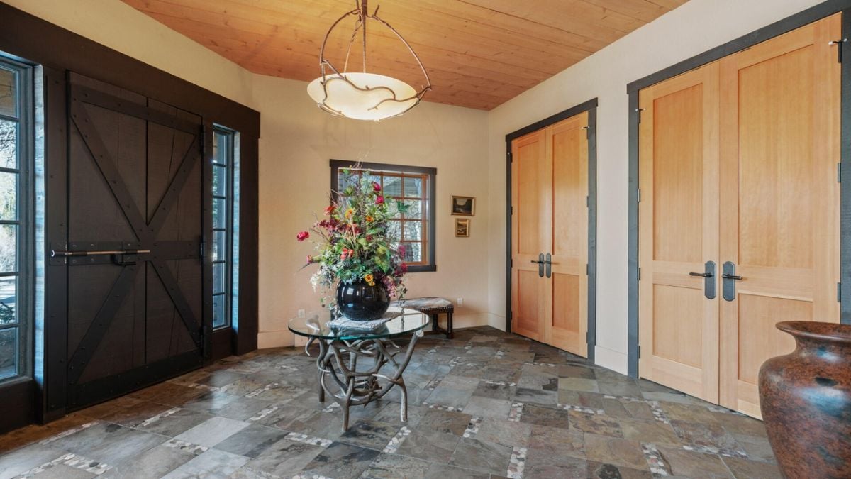 Foyer with a large door, chandelier and tile flooring.