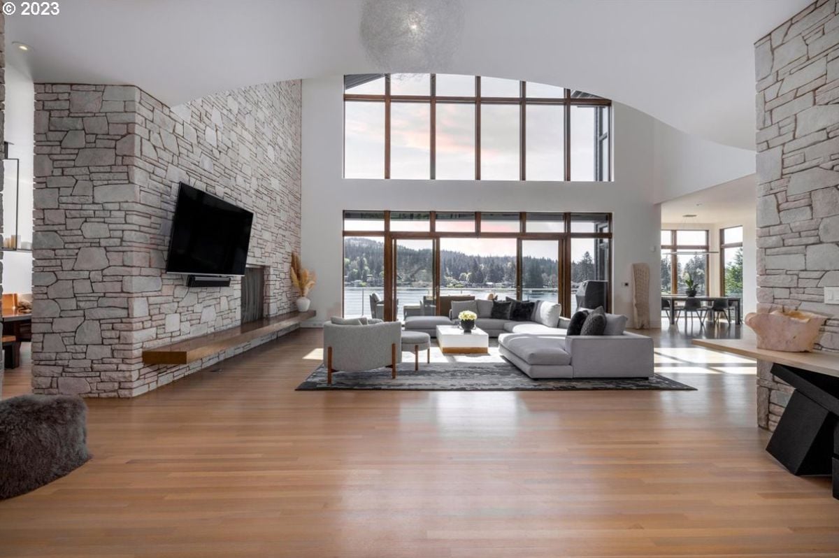 Living room with couches, wood flooring, a fireplace, and large glass doors.