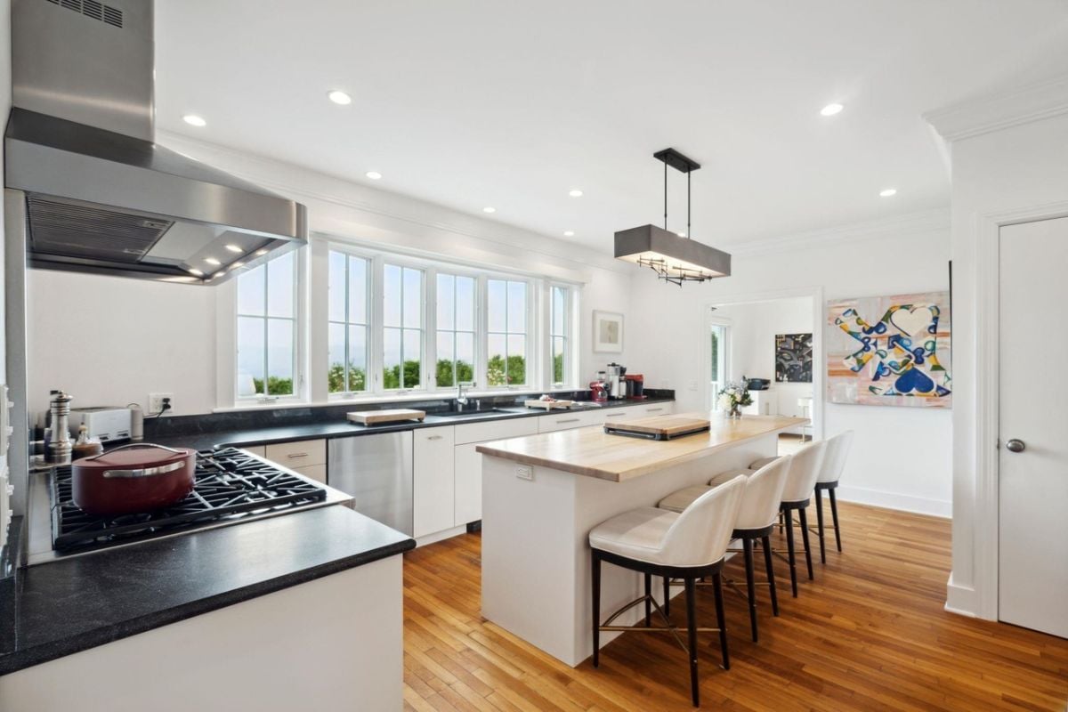 Kitchen with a large island, wood flooring, and custom lighting.