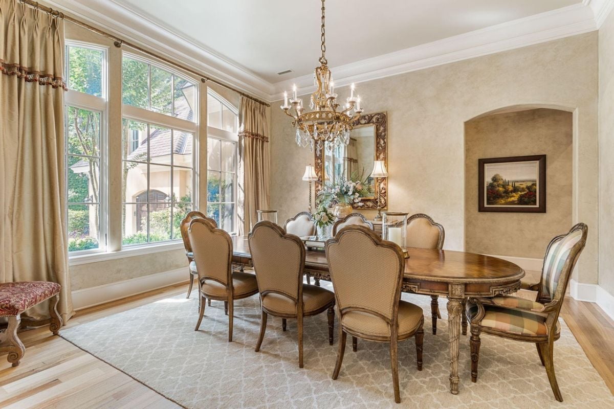 Dining room with a chandelier, large table, and glass windows.