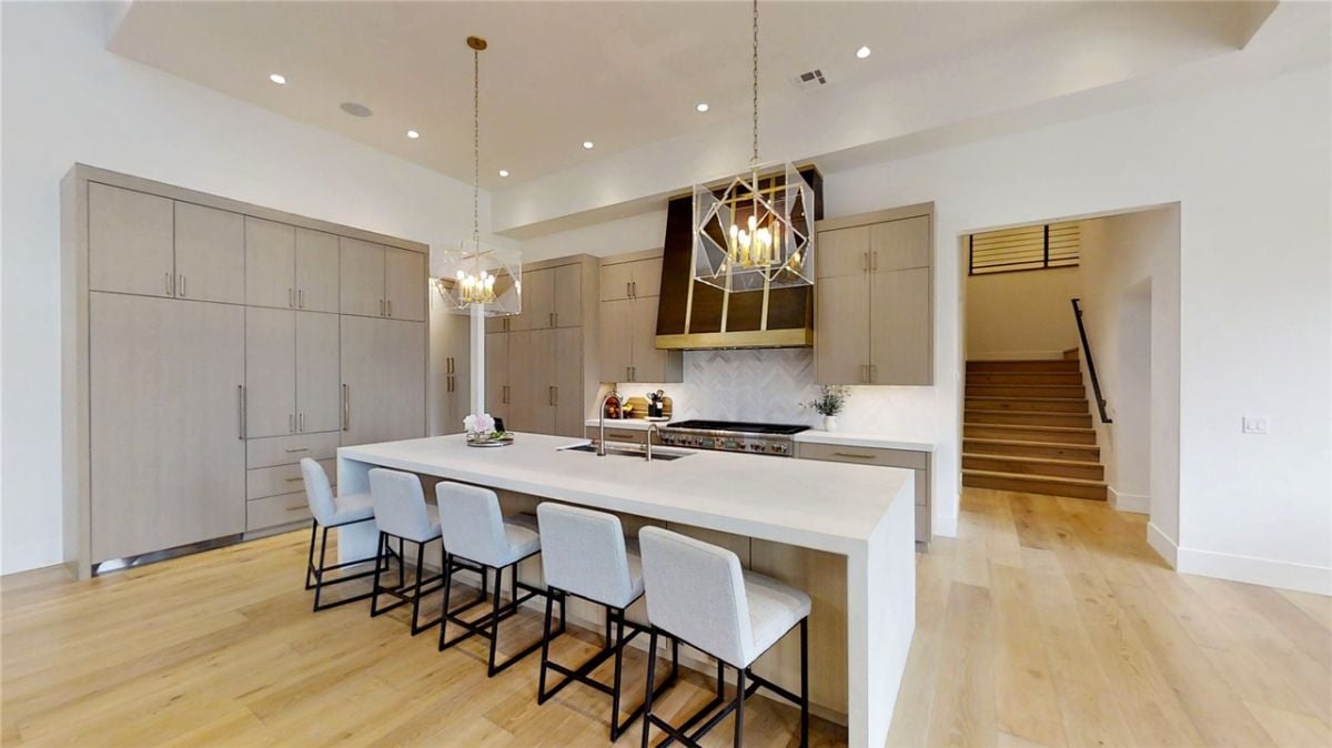 Kitchen with a large island, wood flooring, custom cabinetry, and custom lighting.