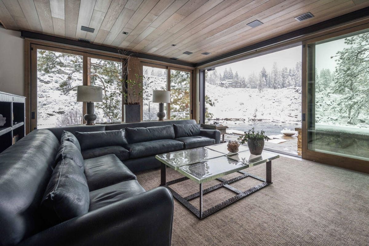 Living room with couches and large glass windows overlooking the river.