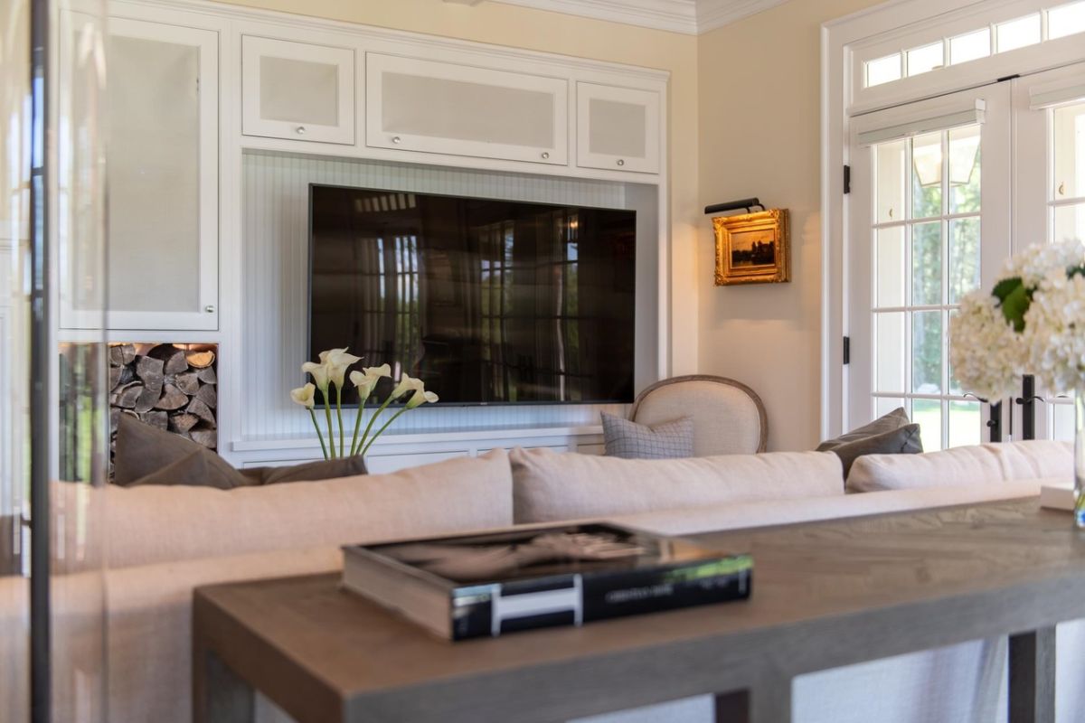 Living room with a large TV, couch and glass doors.