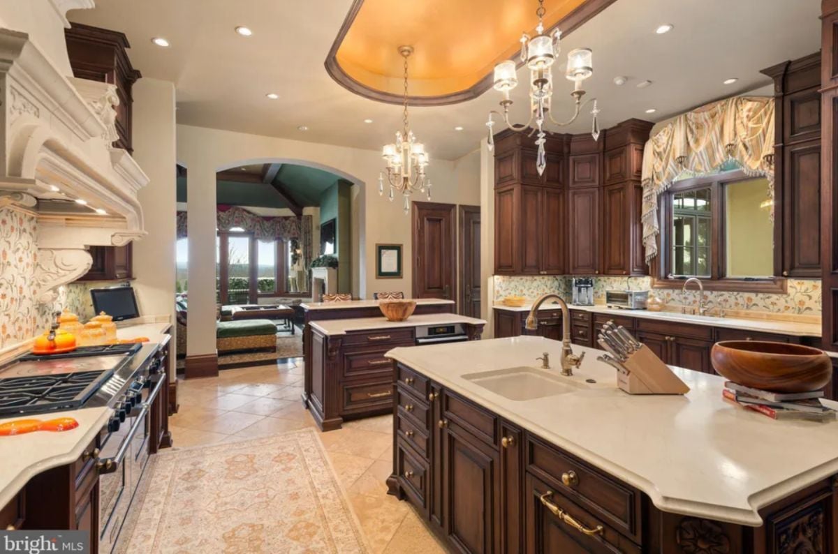 Kitchen with a large island, tile flooring, custom lighting, and sinks.