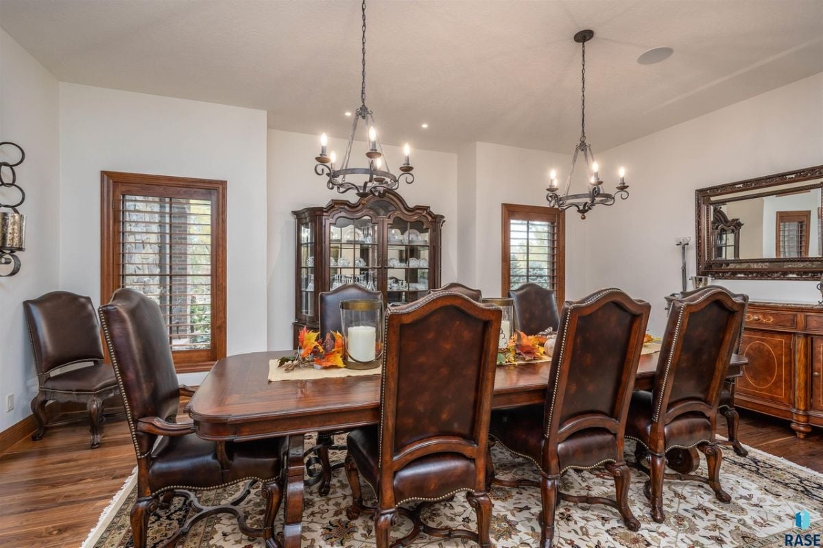 Dining room with chandeliers, a large wooden table and chairs.