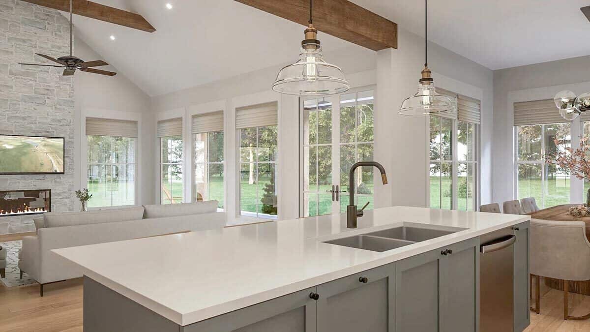 Kitchen island with double sinks, a dishwasher, and views of the great and dining rooms.
