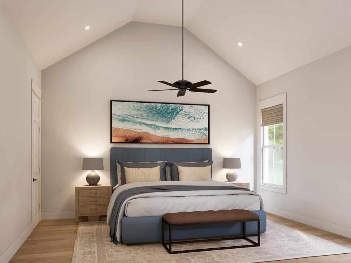 Primary bedroom with a vaulted ceiling and a blue upholstered bed complemented with a tufted bench.