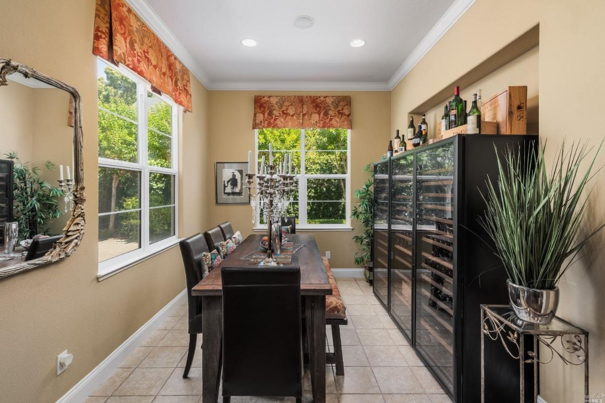 Dining room with a tile flooring, glass windows, wooden table and chairs.