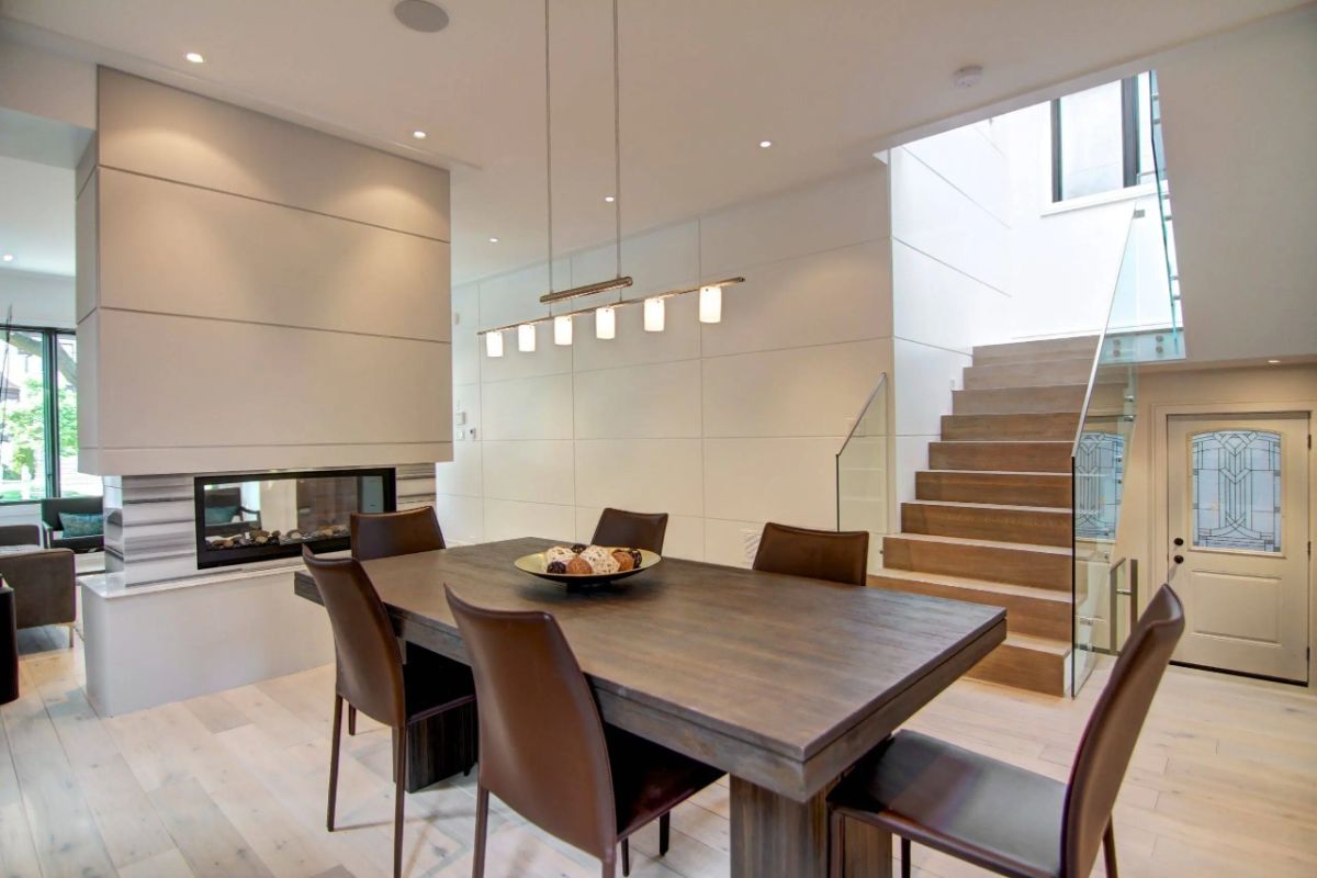 Dining room with custom lighting, a table, chairs, and a fireplace.