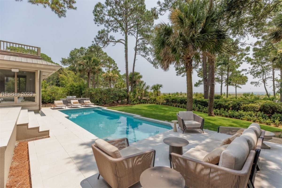Pool with lounge chairs and a view of the ocean.
