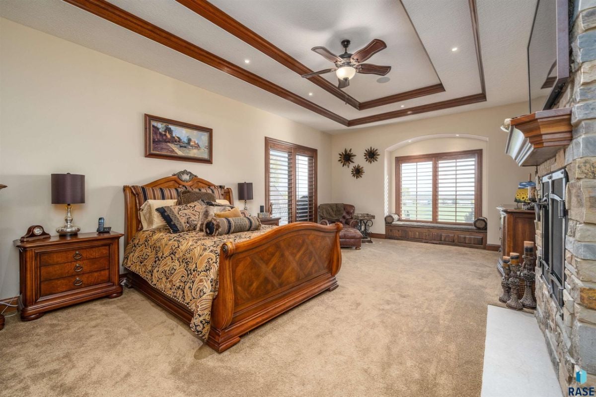 Bedroom with carpet flooring, custom lighting and a fireplace.