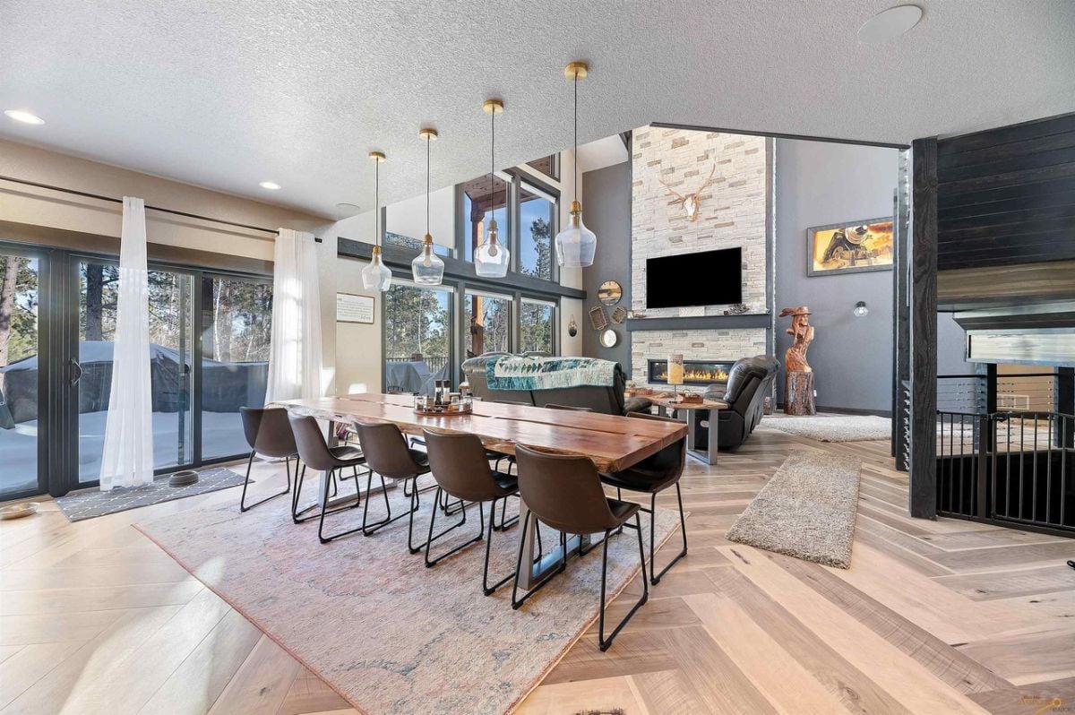 Dining room with custom lighting, wood flooring and a large wooden table.