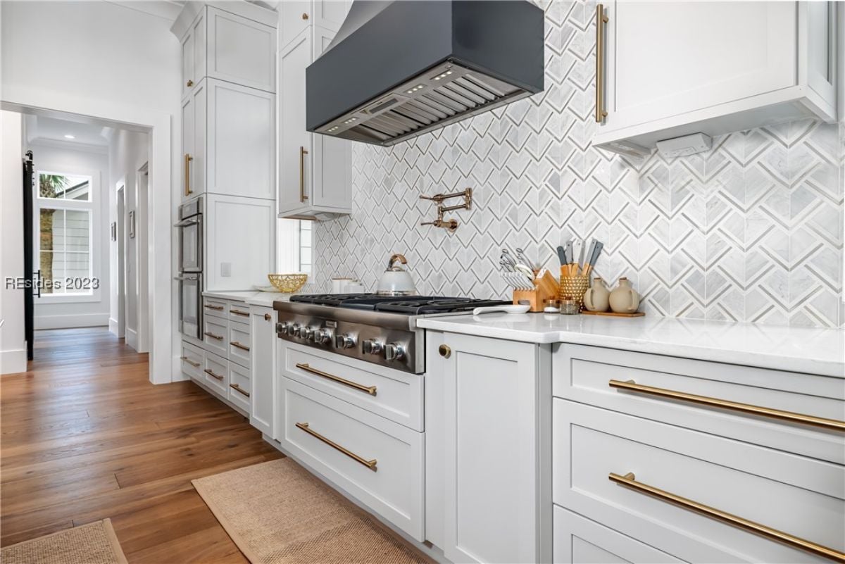 Kitchen with custom white cabinetry and wood flooring.