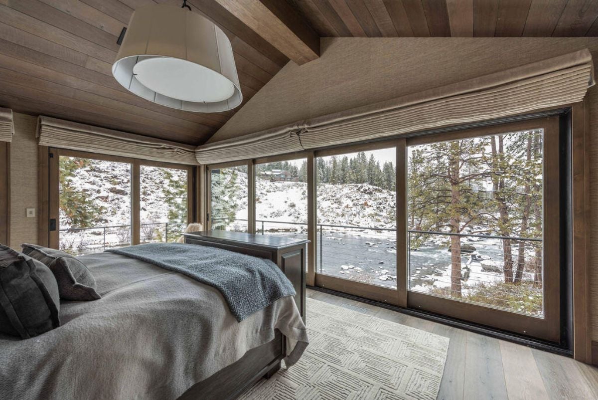 Bedroom with large glass windows overlooking the river.