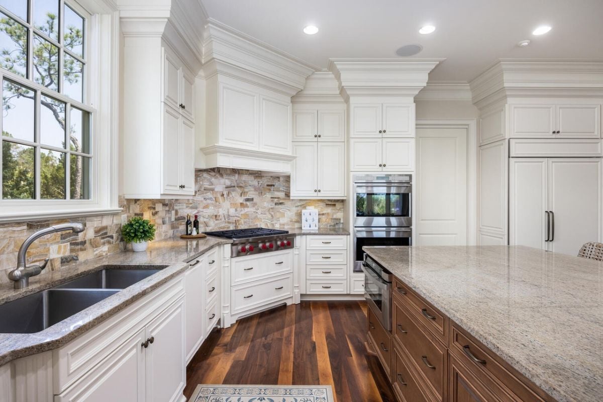 Kitchen with white cabinets, custom lighting, and wood flooring.