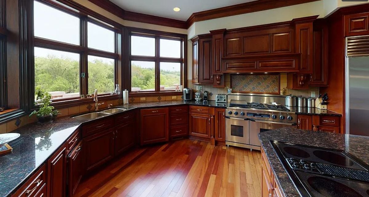 Kitchen with glass windows, wooden cabinets and granite counter tops.
