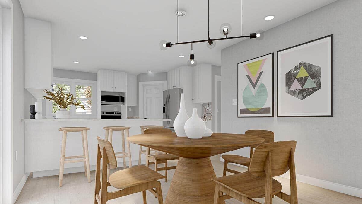 Dining area with wooden chairs and a matching round table topped with a linear chandelier.
