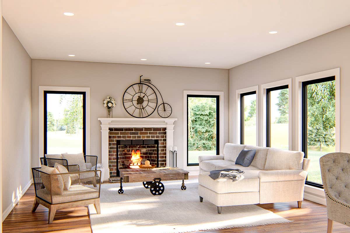 Family room with contemporary seats, a brick fireplace, and tall windows that look out the expansive backyard.