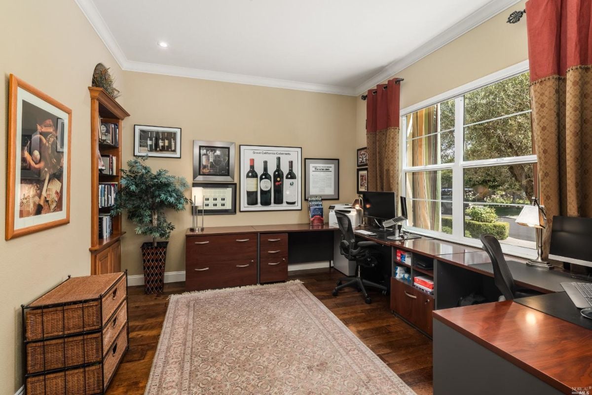 Home office with a desk, computers, and glass windows.