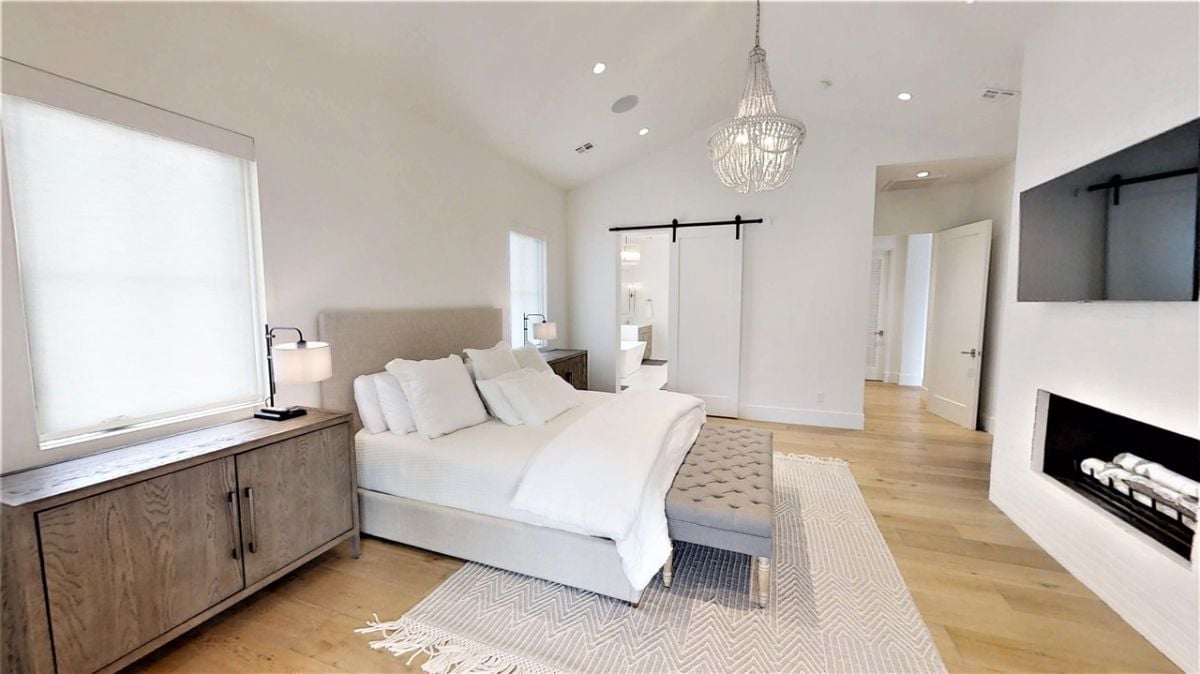 Bedroom with custom lighting, a flat screen TV, and a large bed.