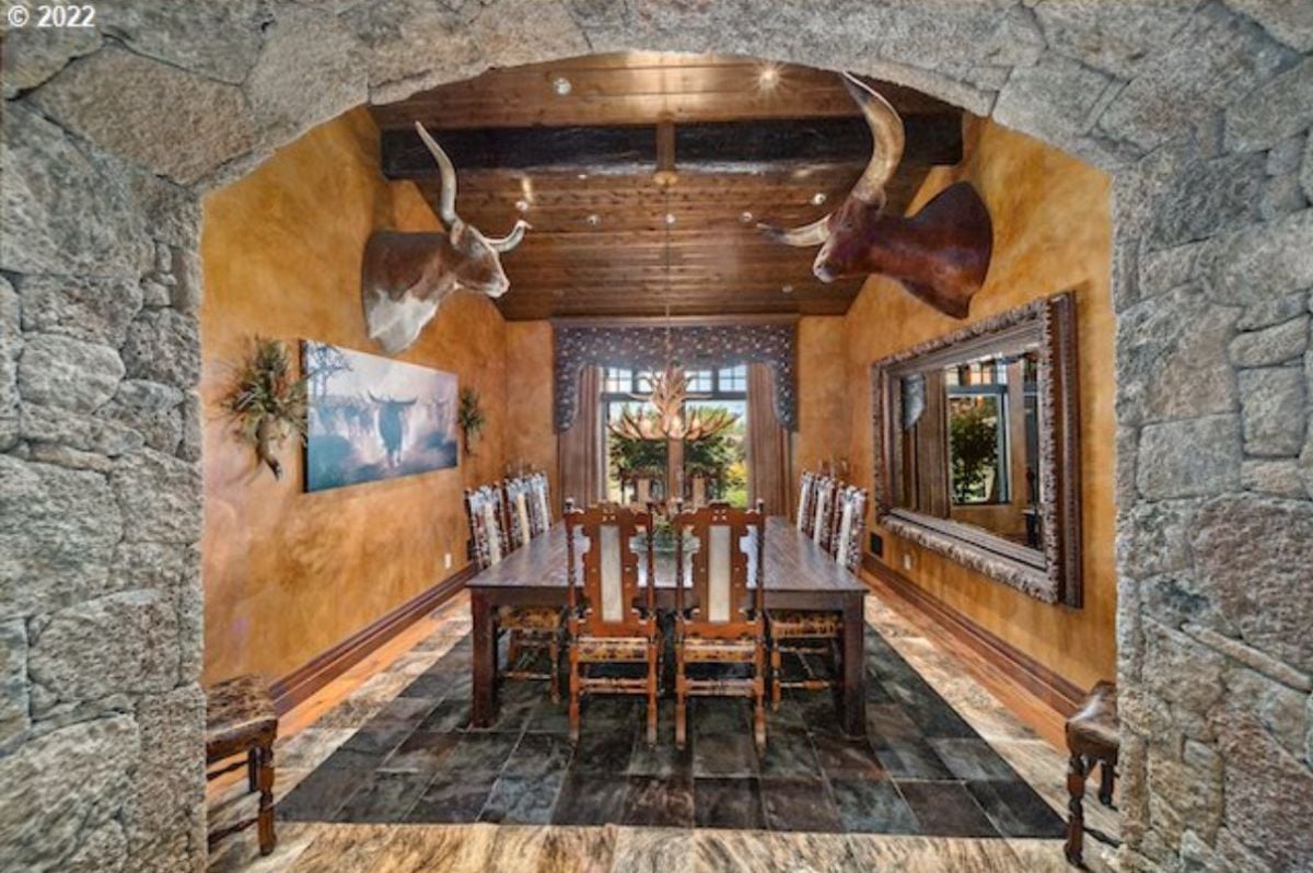 Dining room with stuffed animals on the wall, a large mirror, and a wooden table.
