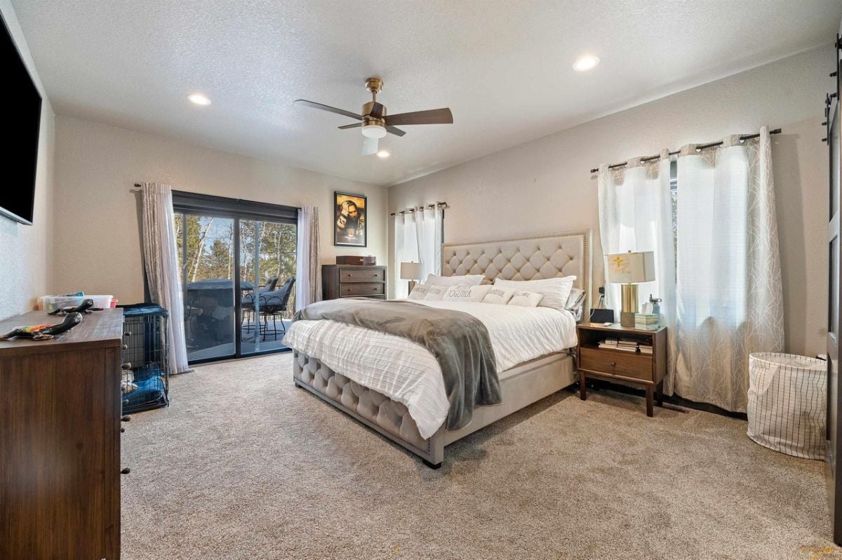 Bedroom with carpet flooring, custom lighting, and sliding doors leading to the balcony.