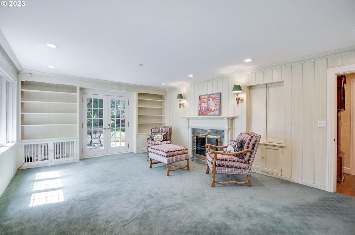 Living room with carpet flooring, a fireplace and glass doors.