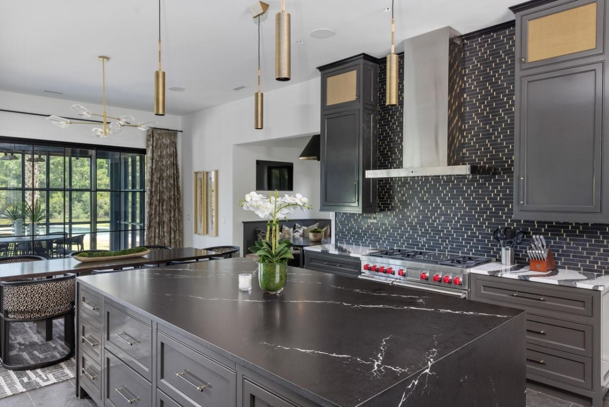 Kitchen with a large island, a stove and black cabinets.