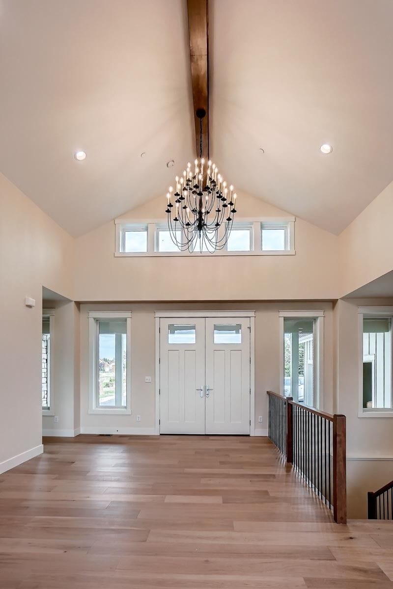 Foyer with transom windows and a cathedral ceiling lined with an exposed beam.
