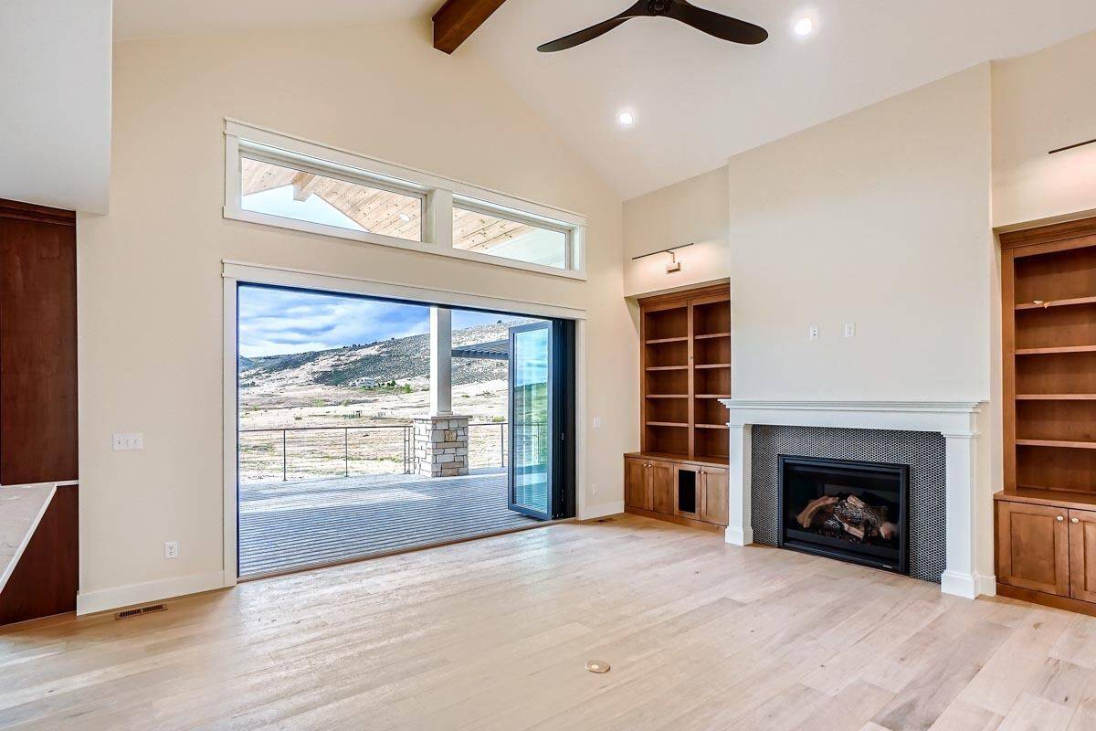 Great room with a fireplace, wooden built-ins, and retractable doors that open onto a covered deck.