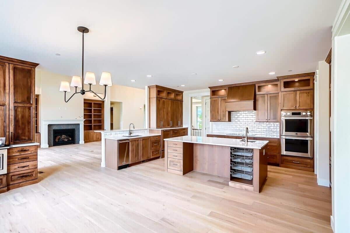 Kitchen with granite countertops, double wall ovens, a center island, and wooden cabinets that blend in with the hardwood flooring.