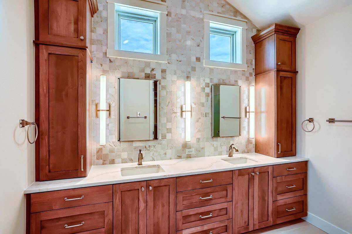 Primary vanity with two sinks, cherrywood cabinets, and chrome-framed mirrors topped with clerestory windows.