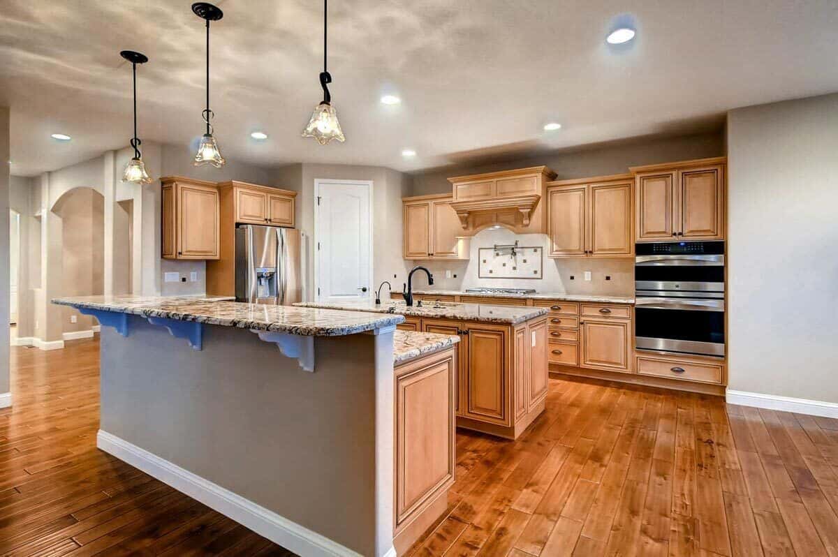 Kitchen with two islands and wooden cabinetry that blends in with the hardwood floor.