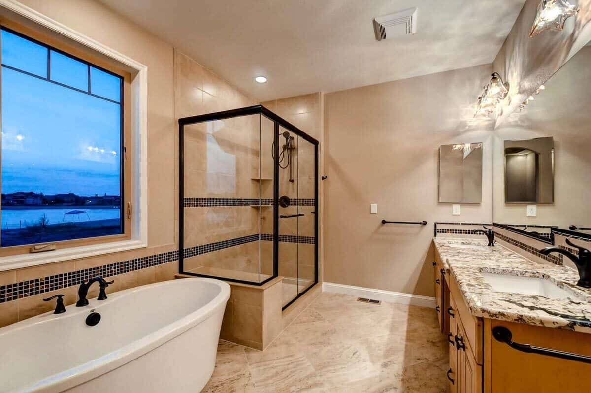 Primary bathroom with a dual sink vanity, a tiled shower and a soaking tub under the picture window.