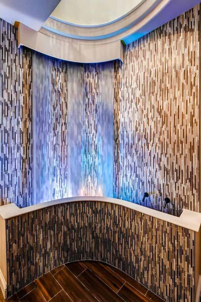 Waterfall feature clad in linear mosaic tiles.