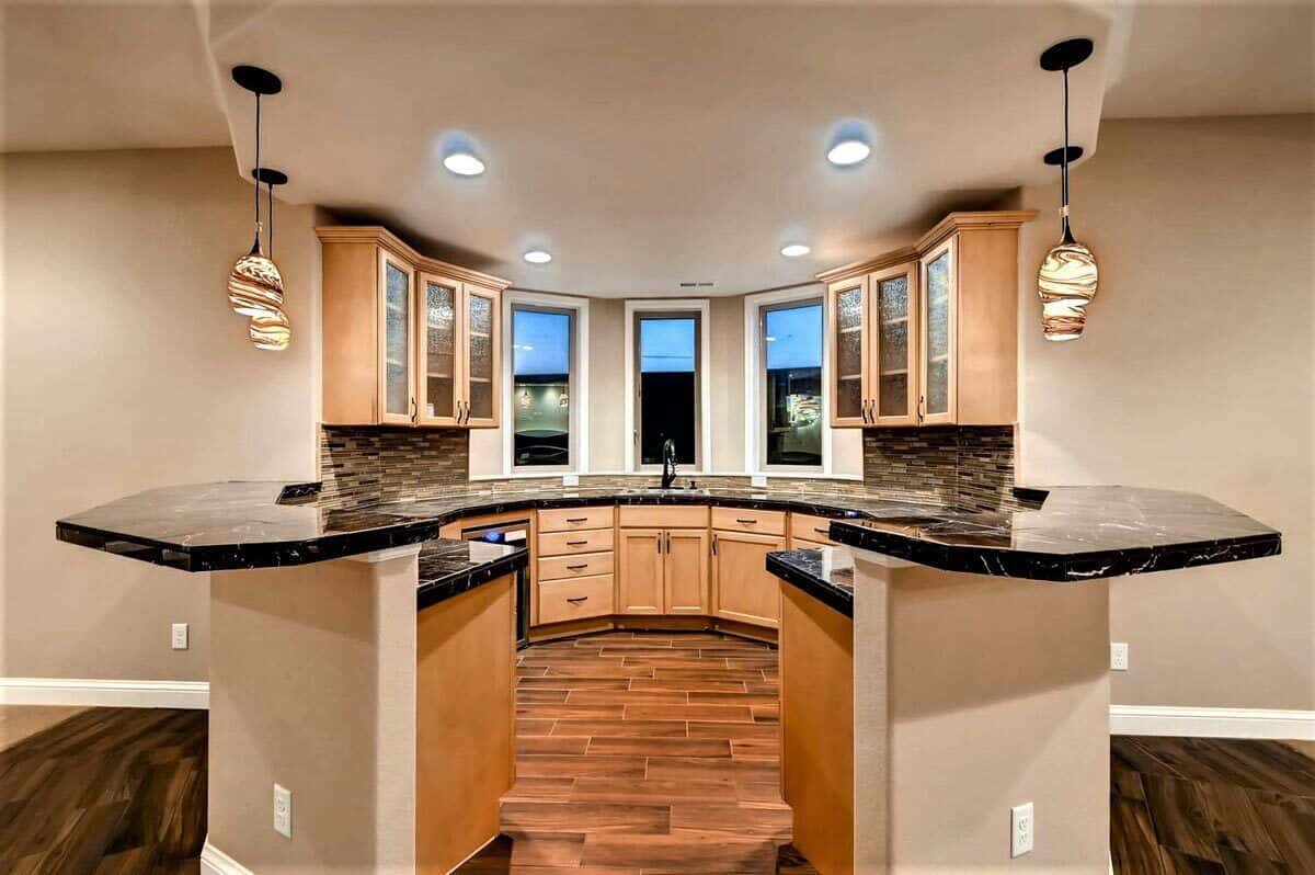 Wet bar with a curved countertop, glass-front overhead cabinets, and a bow window.