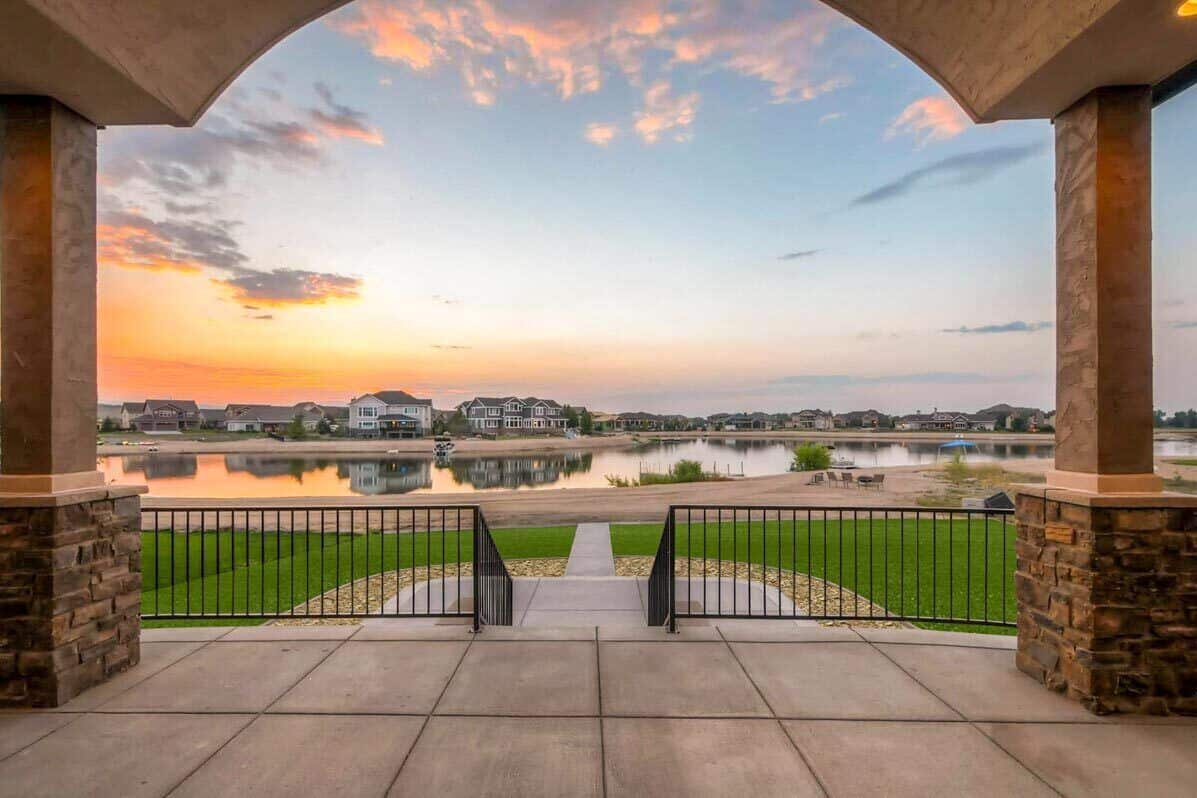 Covered rear porch with wrought iron railings overlooking the surrounding landscape.