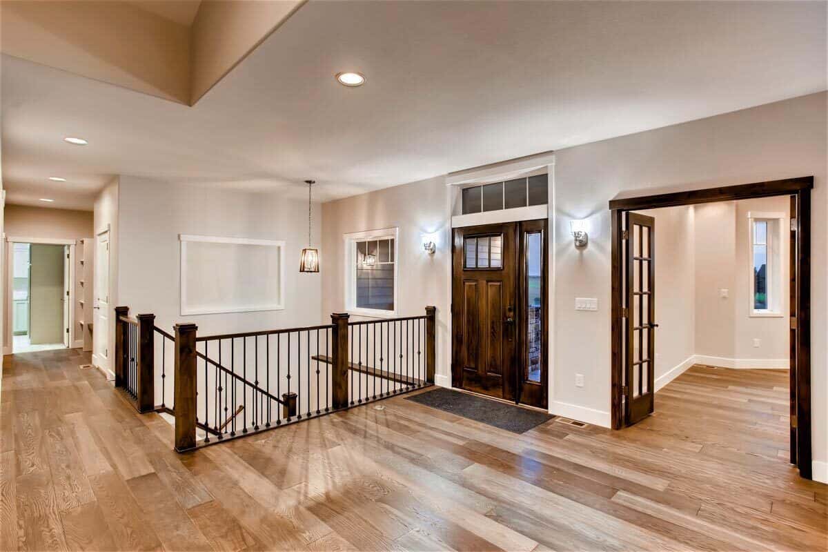 Foyer with a wooden front door, a staircase leading down to the basement, and a French door that opens to the study.