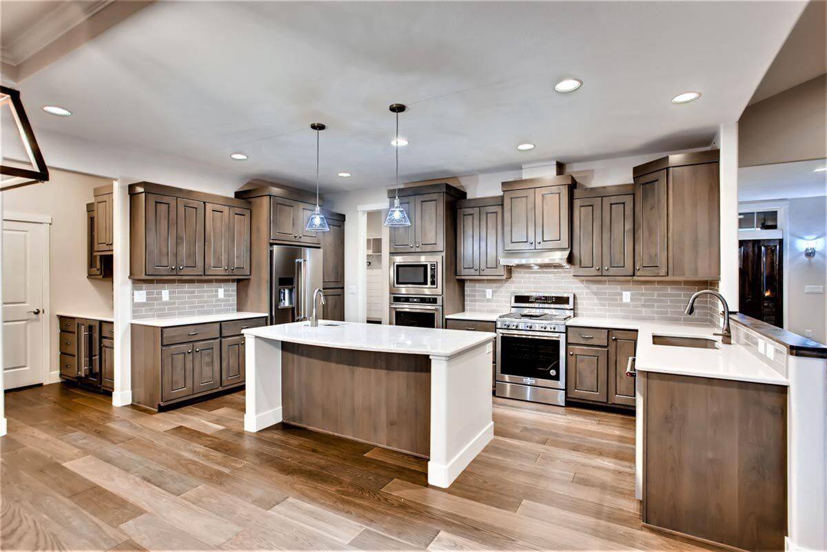Kitchen with a center island, stainless steel appliances, and plenty of wooden cabinetry blending in with the hardwood flooring.