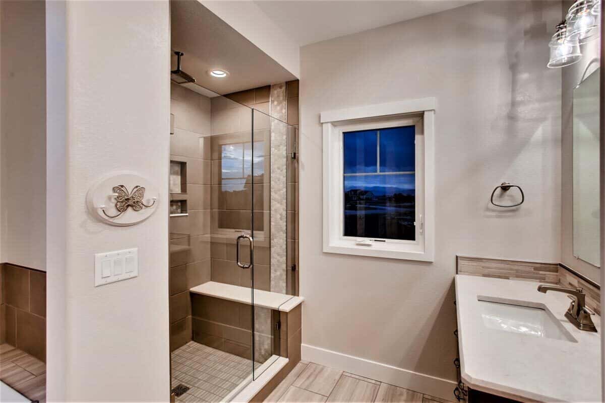 Primary walk-in shower with a glass-hinged door and a tiled bench.