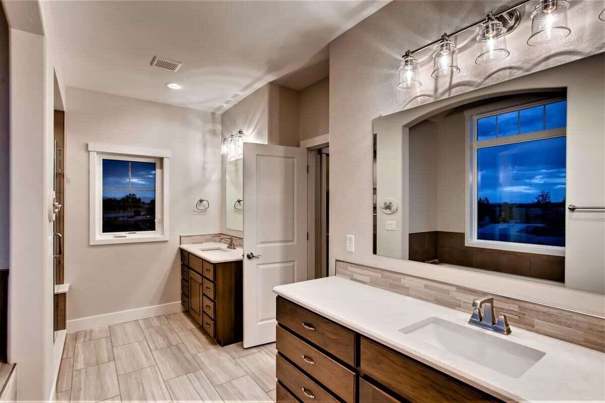 His and her sink vanities topped with frameless mirrors and glass sconces.