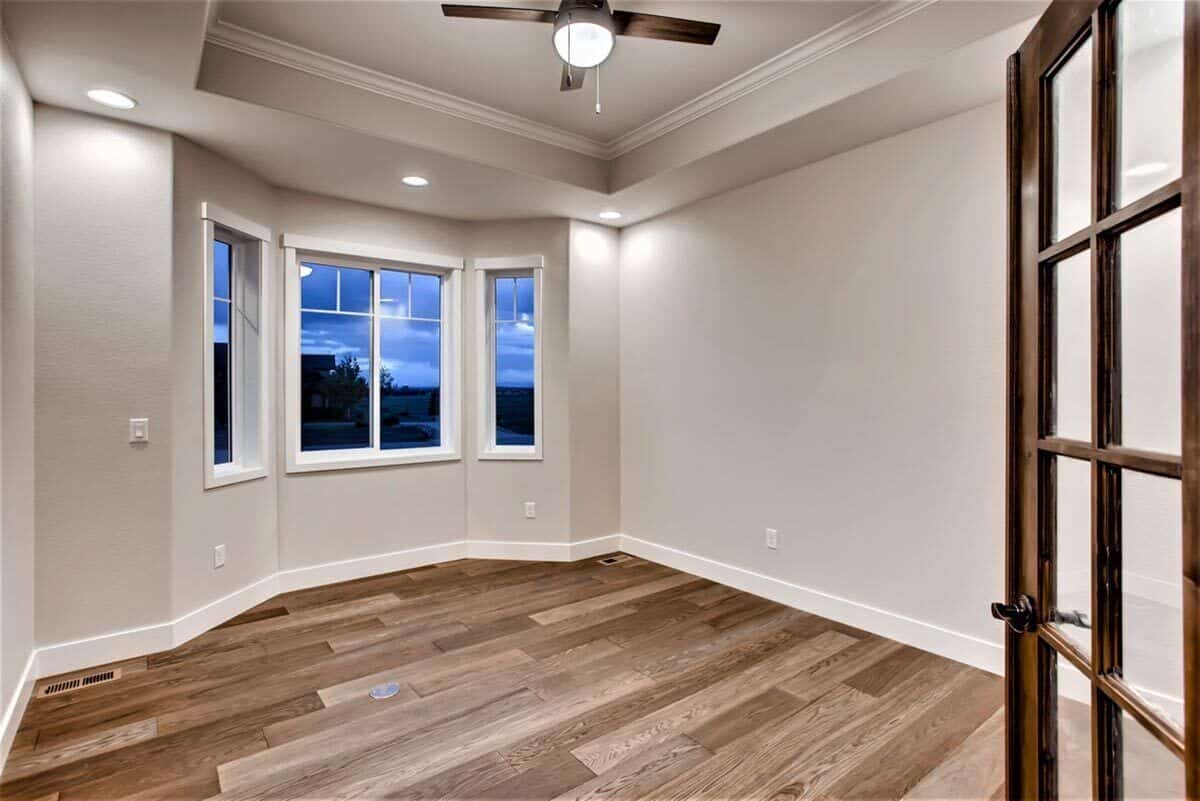Study with a tray ceiling, a bay window, and a hardwood flooring.