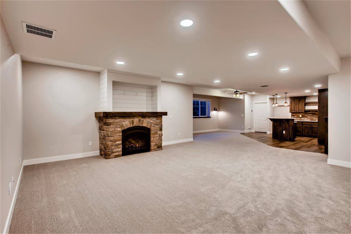 Family room with a stone fireplace and carpet flooring.