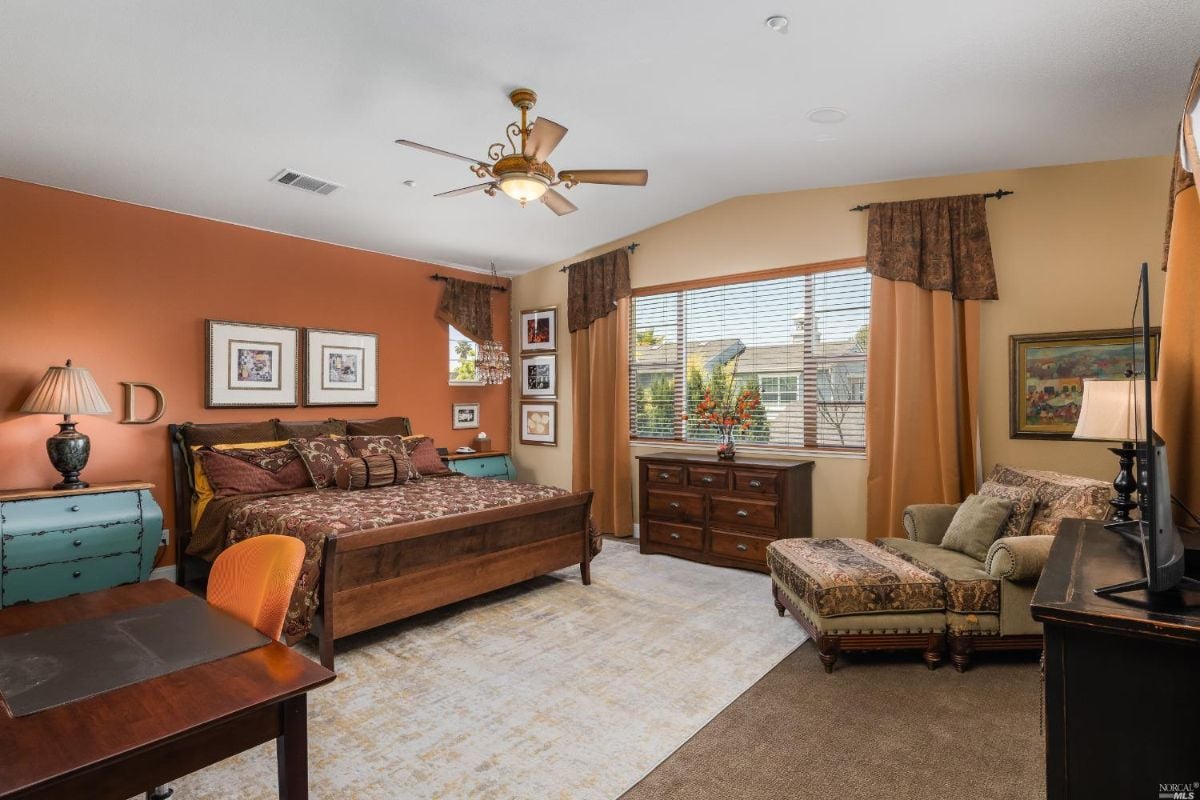 Spacious bedroom with carpet flooring, couch and a large bed.