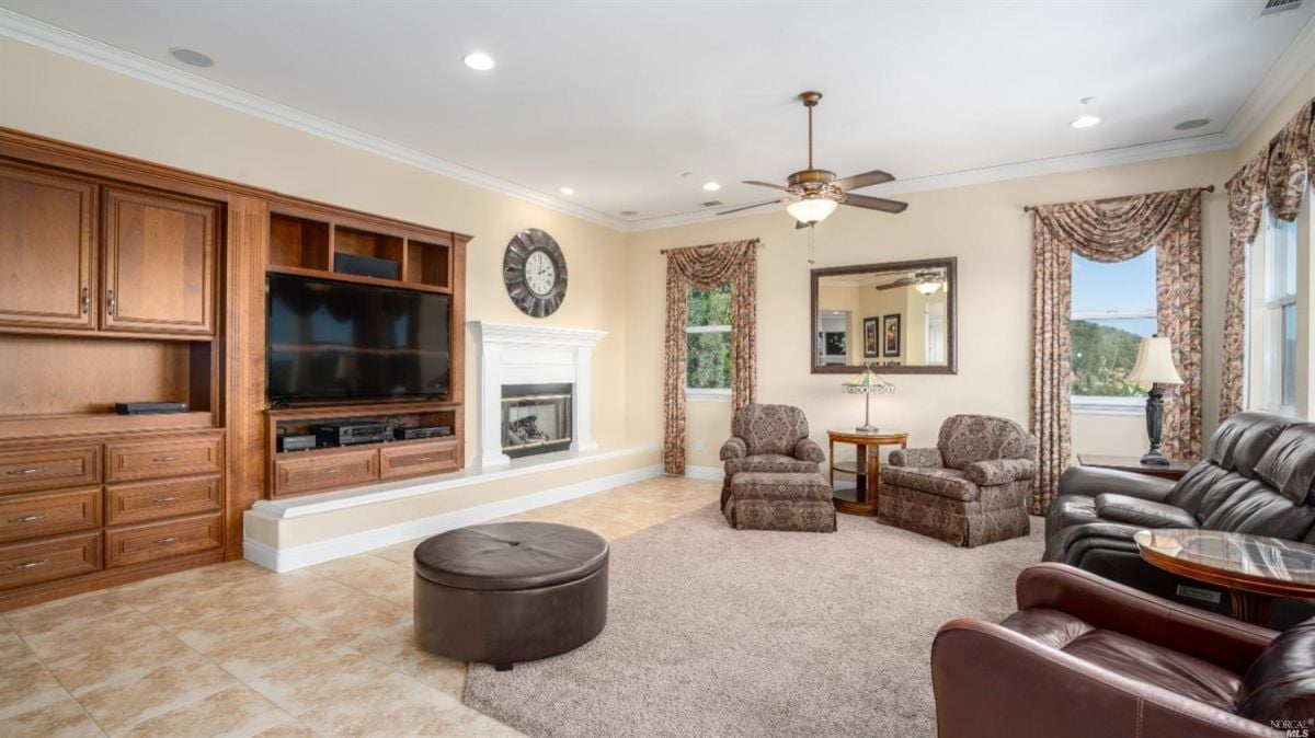 Media room with a large flat screen TV, couches and a ceiling fan.